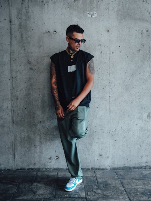 Young Man in a Trendy Outfit Standing against a Concrete Wall