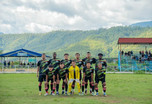 Soccer team posing before a match with a mountainous backdrop.