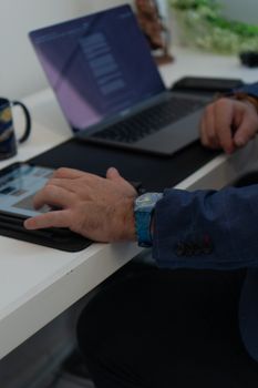 Close-up of a person using a tablet and laptop simultaneously on a desk.