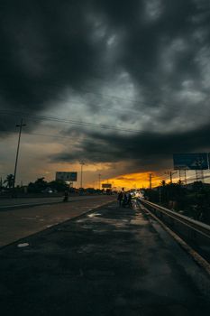 Capture of storm clouds over a city highway at sunset, creating a dramatic urban scene.
