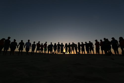 People Standing on Brown Sand during Sunset