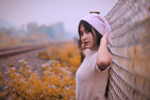 Woman Standing Beside Grey Fence