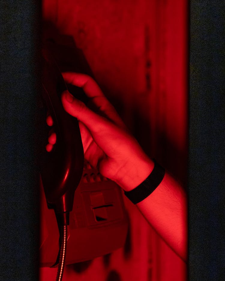 Hand Holding Telephone In Red Light