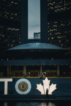 Illuminated Toronto sign with maple leaf at Nathan Phillips Square, city hall in view.