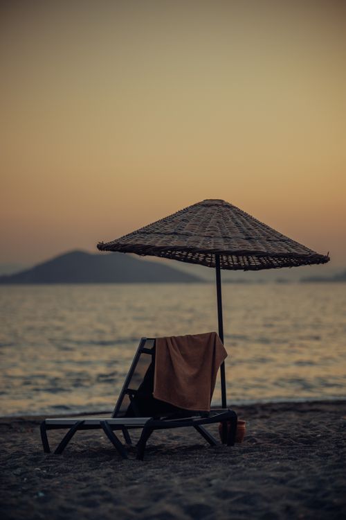 Free Tranquil beach scene with lounger and sunshade at sunrise, capturing a peaceful ocean atmosphere. Stock Photo