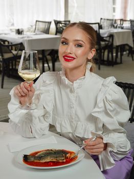 Woman enjoying a fine meal with white wine in a restaurant setting, showcasing elegance and enjoyment.