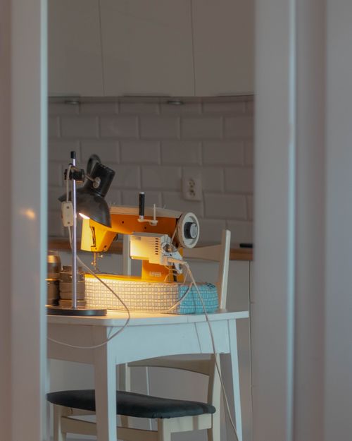 Free A tranquil sewing setup with sewing machine and lamp in a modern kitchen environment. Stock Photo
