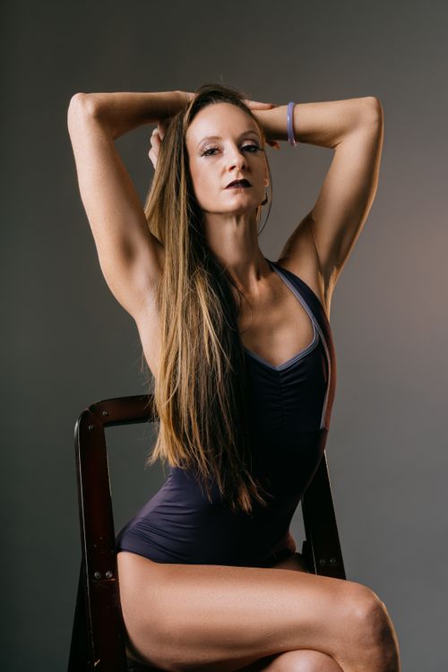 Free Sophisticated portrait of a woman with long hair posing on a chair against a gray background. Stock Photo
