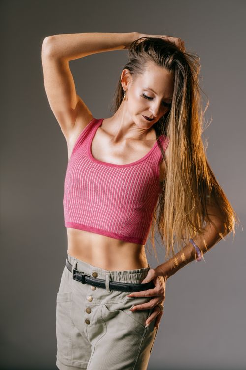 Free Fashionable young woman in a pink top posing confidently in a studio setting. Stock Photo