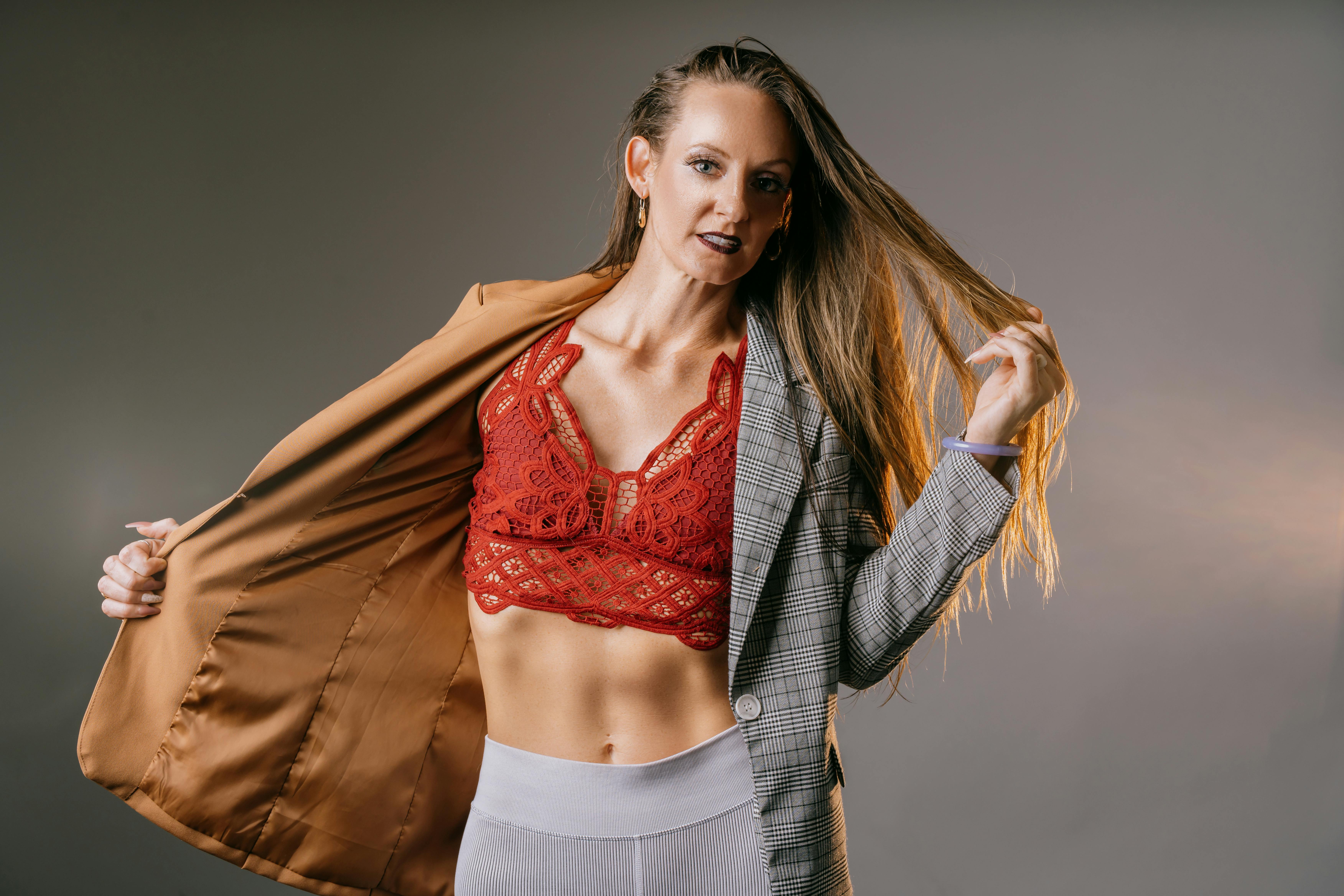 Stylish young woman poses confidently in a fashion-forward jacket with red lace lingerie.