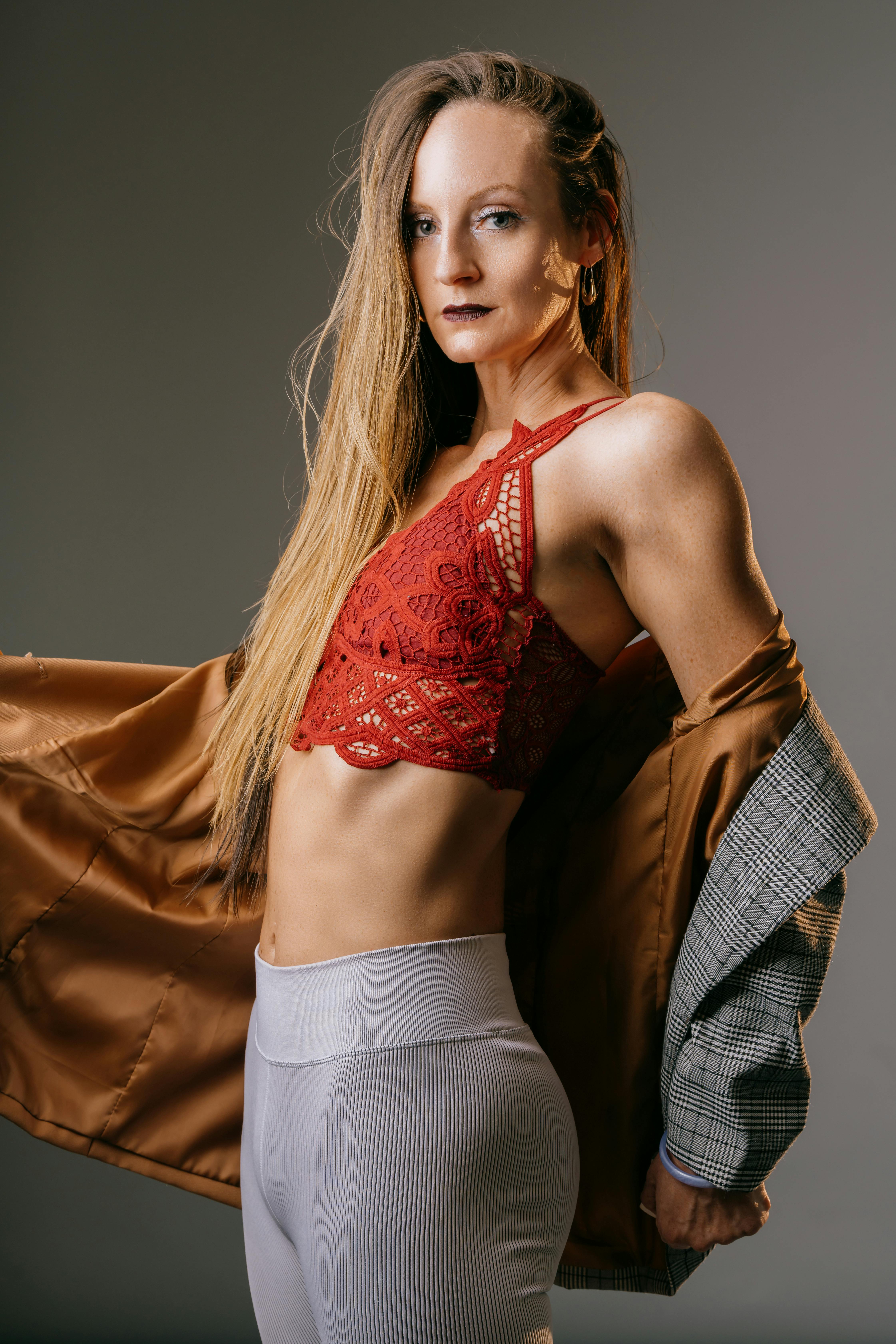 Fashion model poses confidently in modern attire with a red lace top and designer jacket.