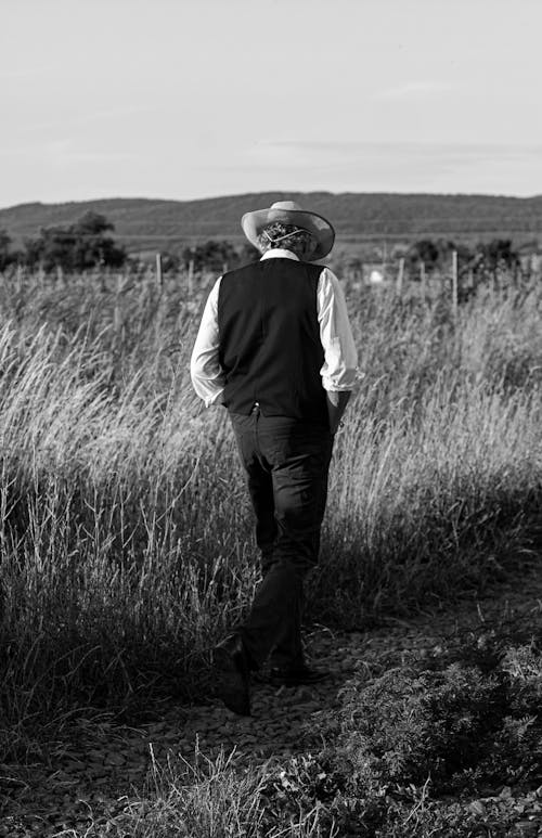 Back View of Man in Hat Walking near Field