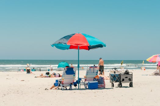 A sunny beach scene in Oceanside with umbrellas and sunbathers enjoying the sand and ocean view.