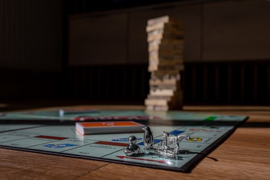 Close-up view of Monopoly board game with metal tokens and stacked Jenga blocks on a table.
