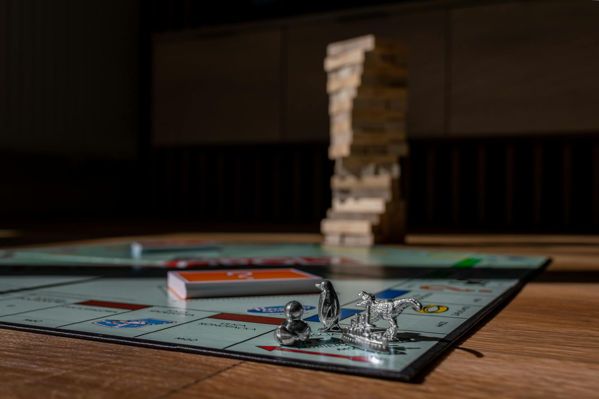 Close-up view of Monopoly board game with metal tokens and stacked Jenga blocks on a table.