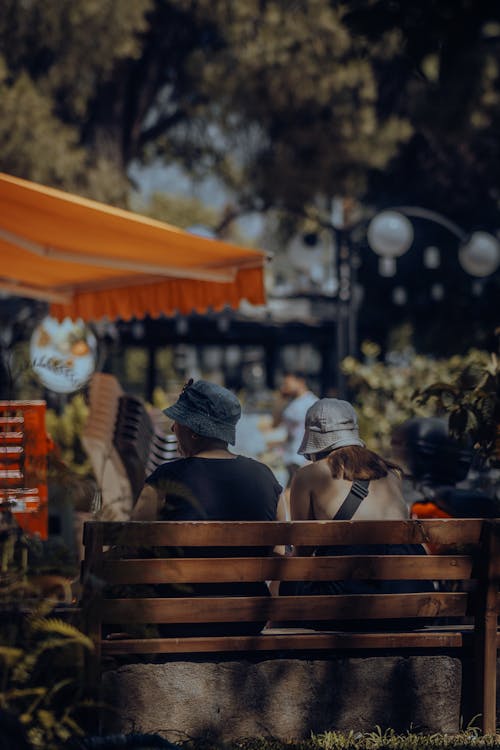 People in Hats Sitting on Bench in Park