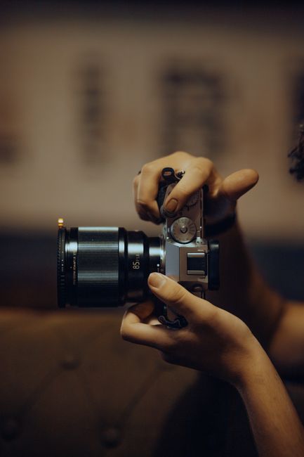 Hands holding and adjusting a camera lens for photography. Selective focus on camera details.