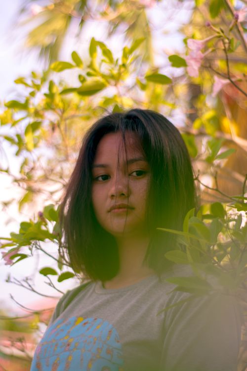 Free A serene portrait of a young woman outdoors surrounded by lush foliage. Stock Photo