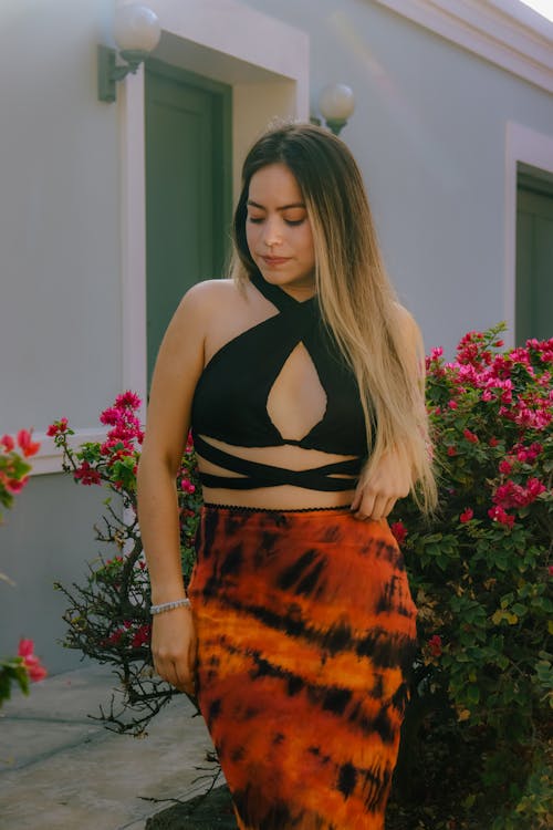 Woman in a Black Top and Orange Skirt in the Garden
