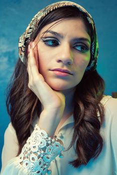 Elegant portrait of a woman with a retro look and floral headband, in a serene setting.