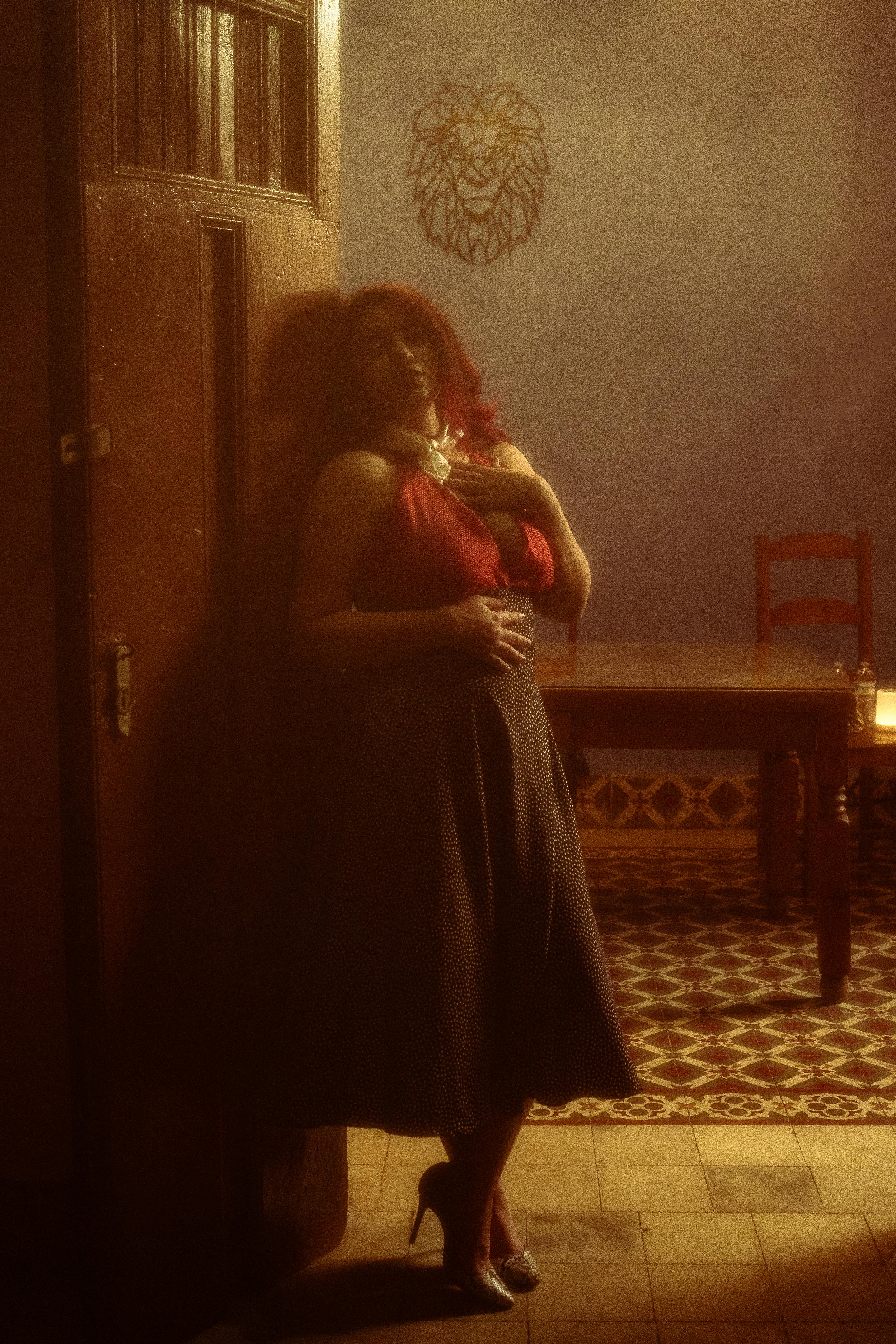 A woman in a stylish outfit stands gracefully in a vintage-themed room in Mérida, México.