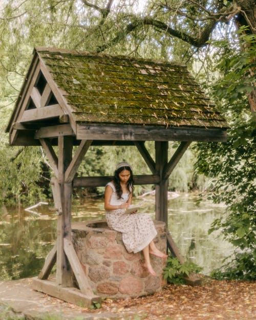 Woman in Dress Sitting on Well in Forest