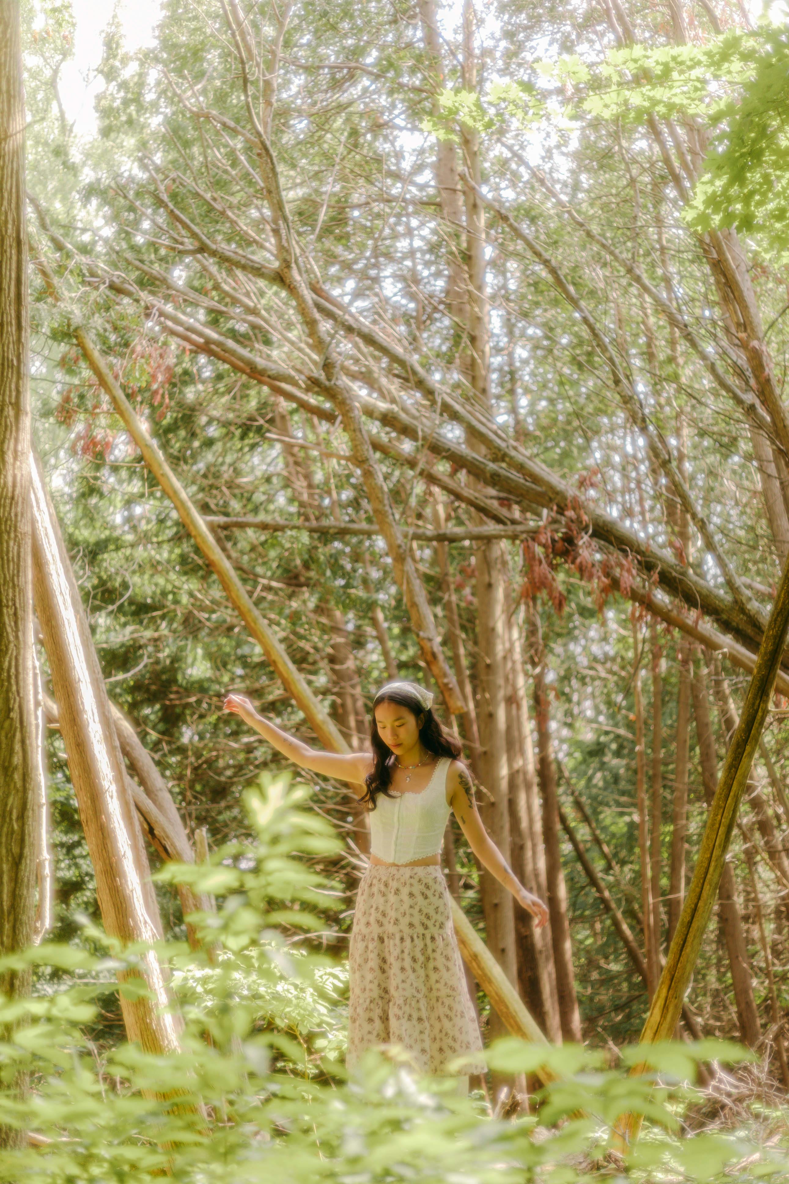A carefree young woman in a skirt enjoying a sunny summer day in a lush forest.