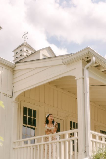 Woman stands on a white wooden porch, enjoying a serene day.