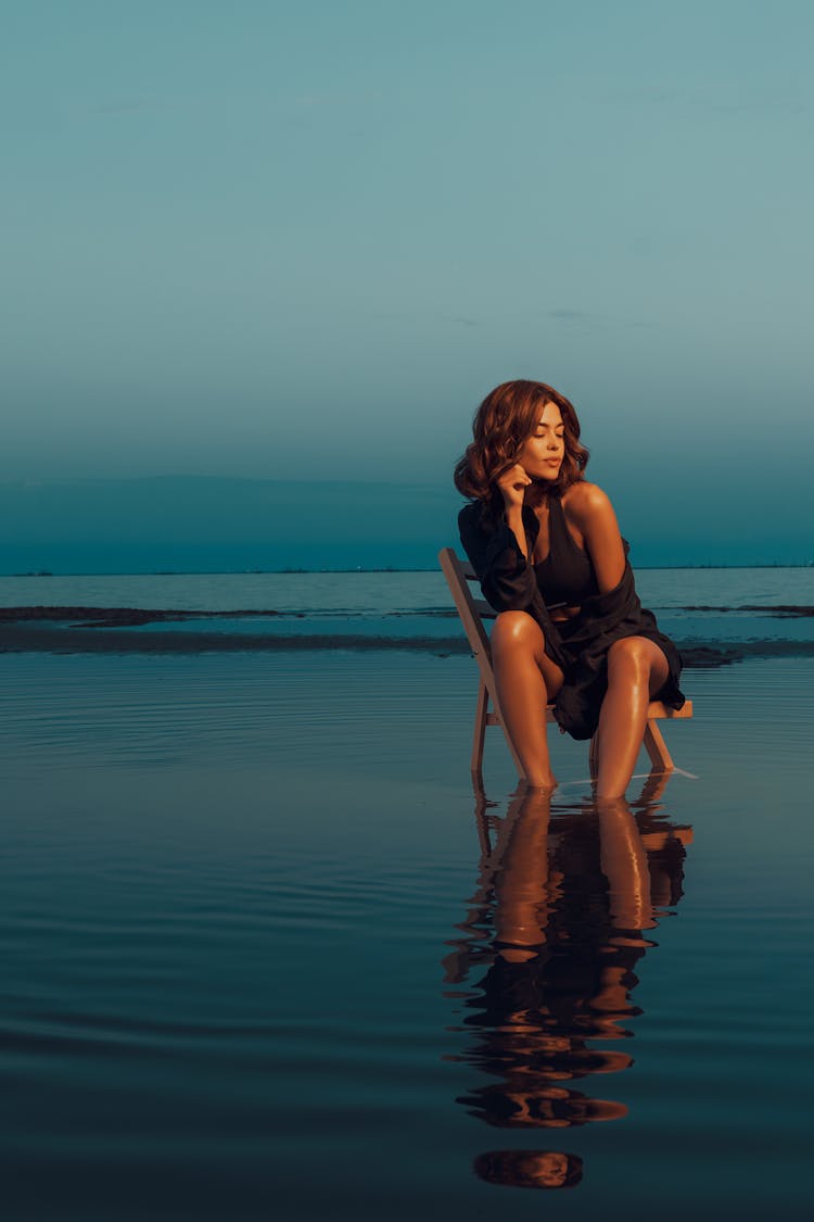 Young Woman Sitting On A Chair In Water 