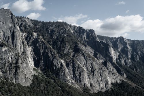 Free Breathtaking view of rugged mountains and dense forest under a cloudy sky. Stock Photo