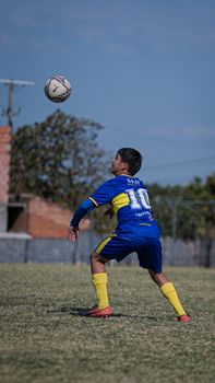 A young soccer player in blue and yellow gear focuses on heading the ball during a match.