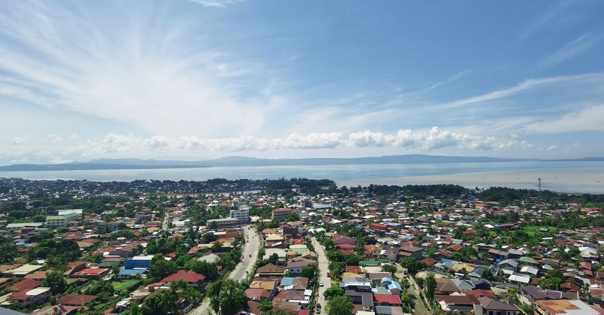 Aerial view of Davao City with a vast coastline and scenic Samal Island in the background.