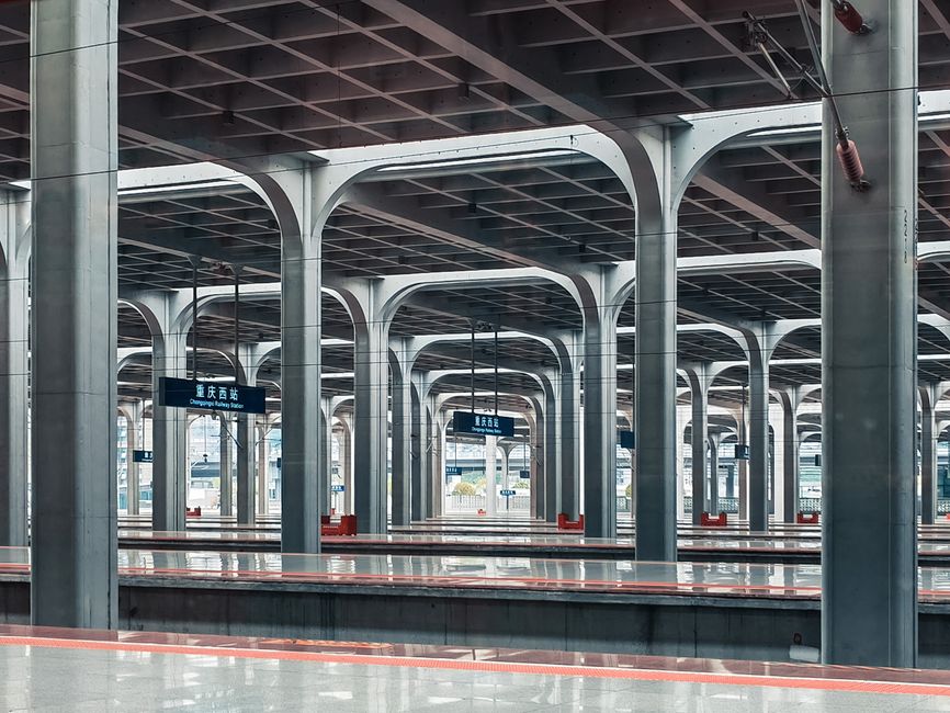 Spacious railway station showcasing modern architectural design with repetitive steel columns.