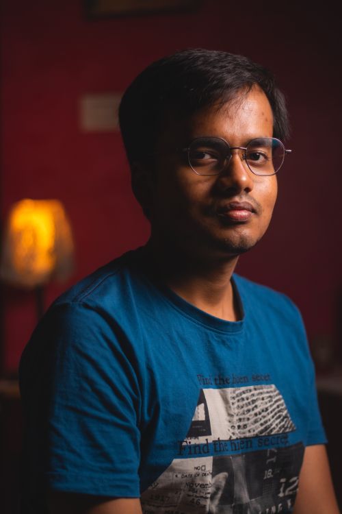 Free Portrait of a man wearing glasses and a blue shirt, taken indoors with soft lighting. Stock Photo