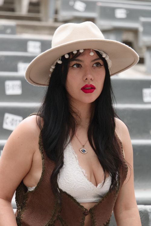 Free Portrait of a woman in a wide-brim hat with red lipstick, sitting outdoors. Stock Photo