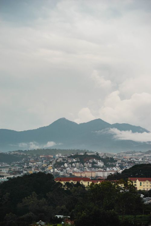 Free Breathtaking view of Dalat city with lush greenery and rolling mountains under a cloudy sky. Stock Photo