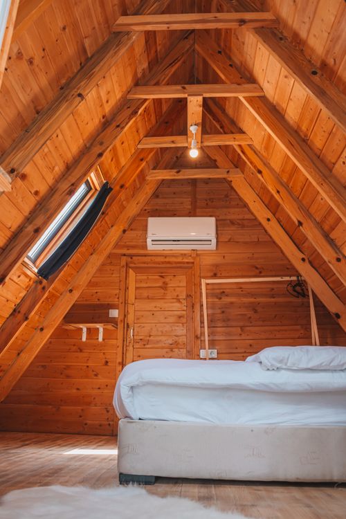 Free Warm wooden attic bedroom with bed and natural light in Kemer, Türkiye. Stock Photo