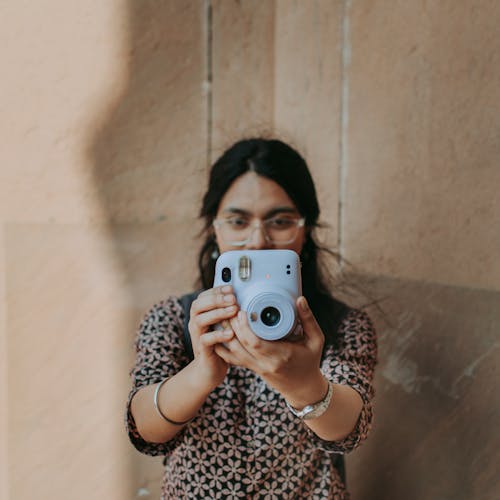 Young Woman in Eyeglasses Holding a Fujifilm Instax Camera