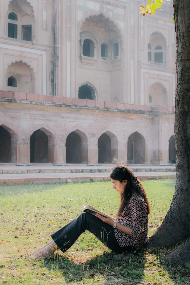 Woman Sitting On Grass And Reading