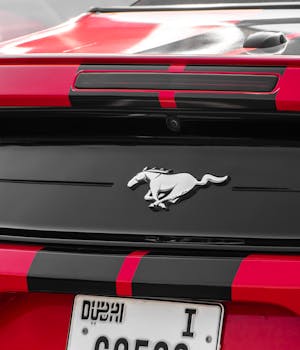 Red sports car with an iconic emblem captured from the back, showcasing luxury and style.