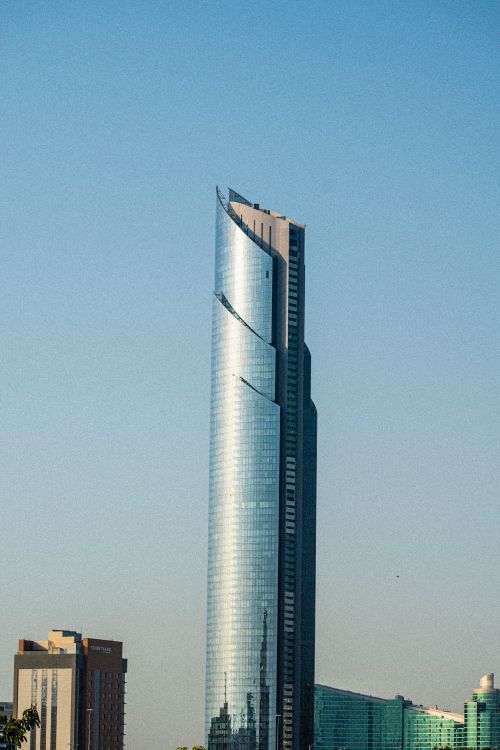 Free Tall futuristic skyscraper with sleek design against a clear blue sky. Stock Photo