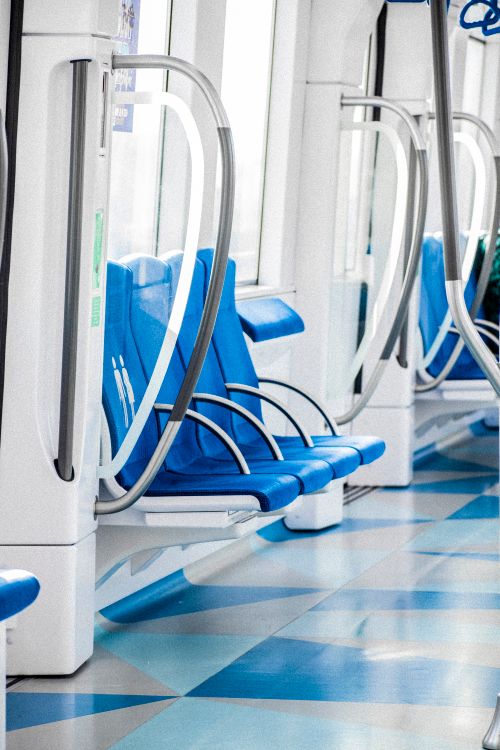 Free Brightly lit urban train interior featuring sleek blue seating, emphasizing modern public transportation. Stock Photo