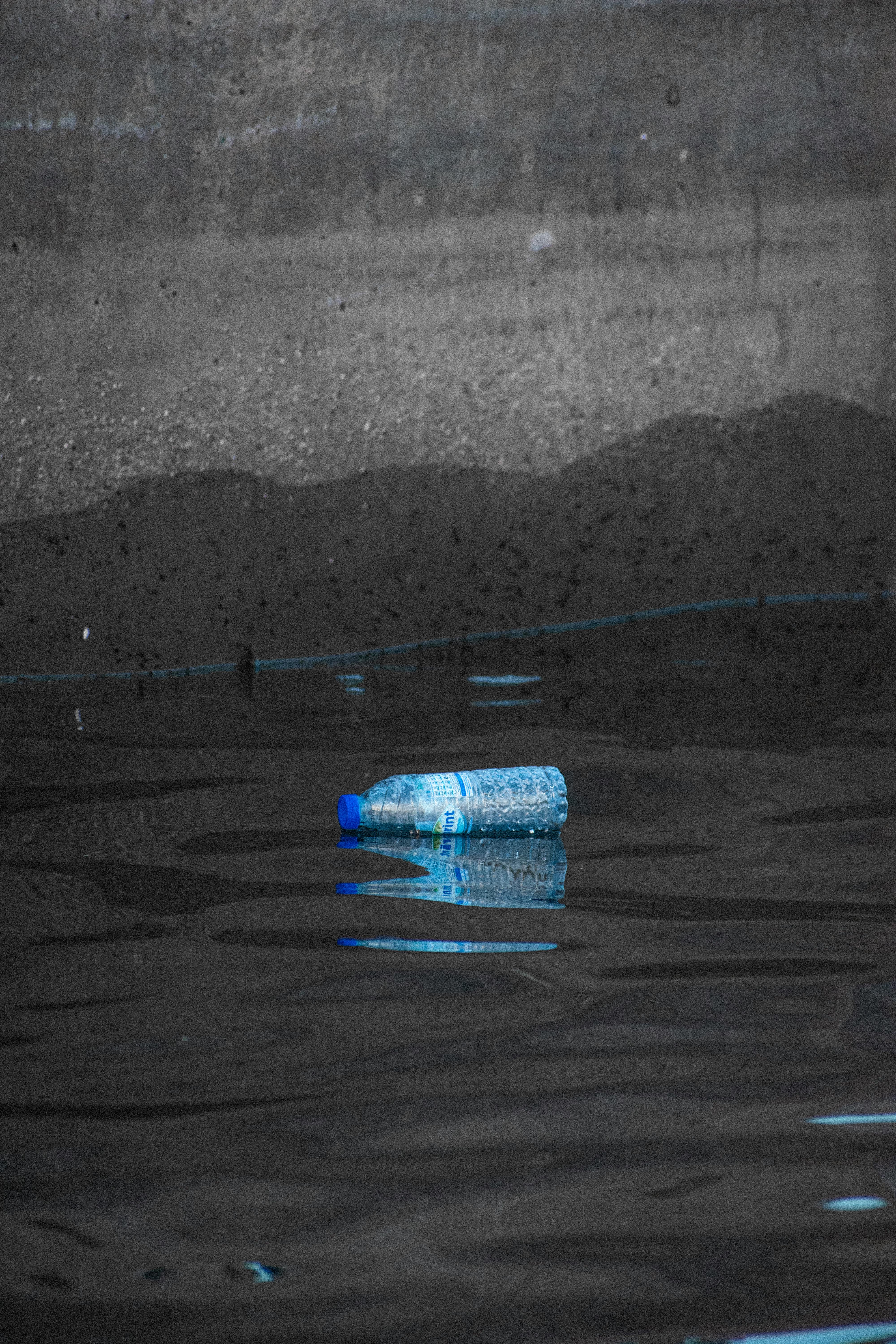 Water Bottle Lying Down on Puddle · Free Stock Photo