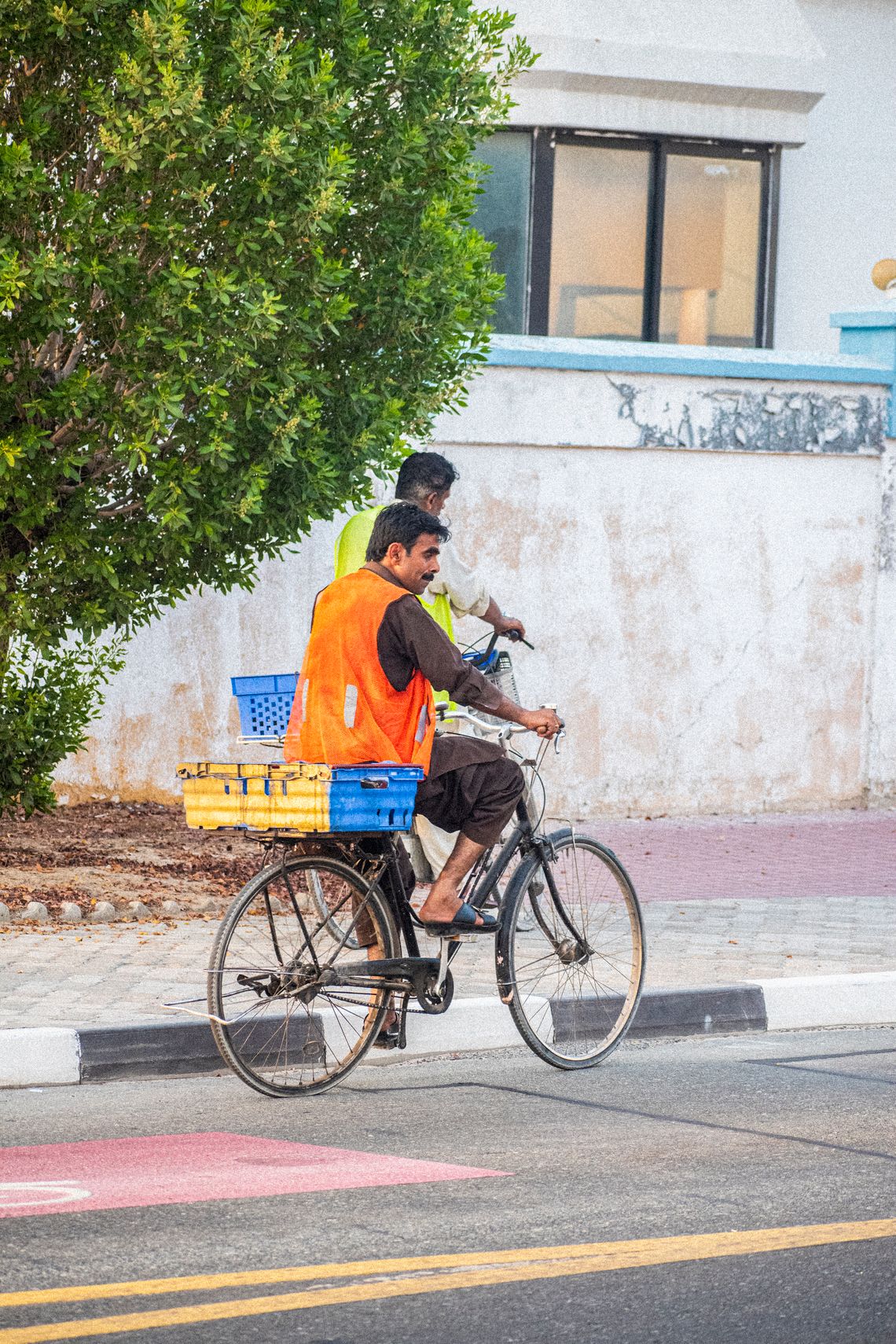 Two cyclists wearing reflective safety vests while riding through a city street