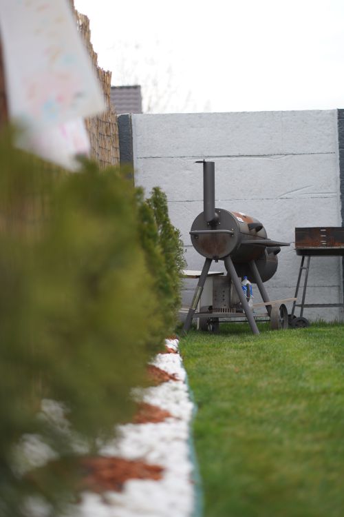 Free Barbecue grill in a lush garden with green grass and privacy wall. Stock Photo