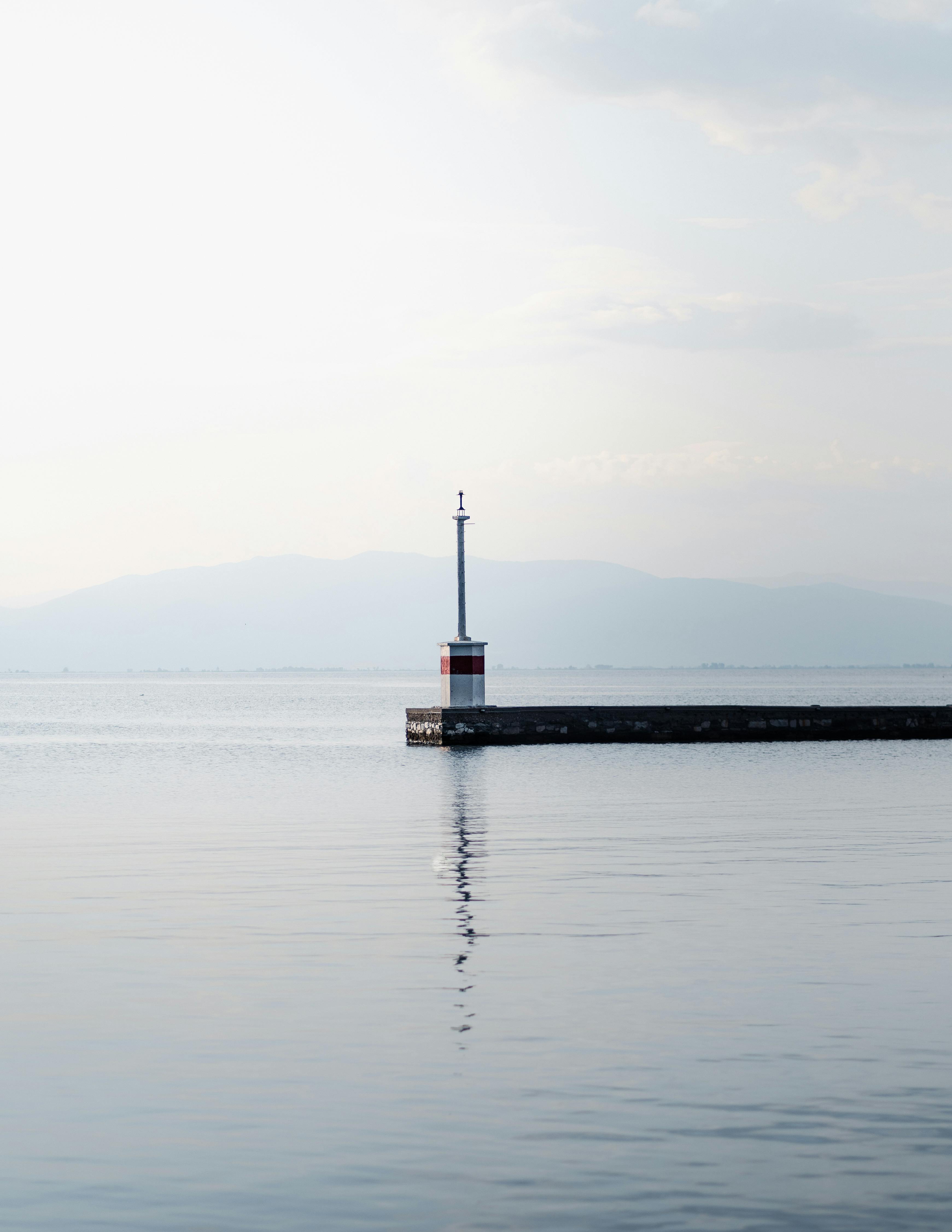 Serene seascape featuring a solitary lighthouse on a misty pier, reflecting tranquility.