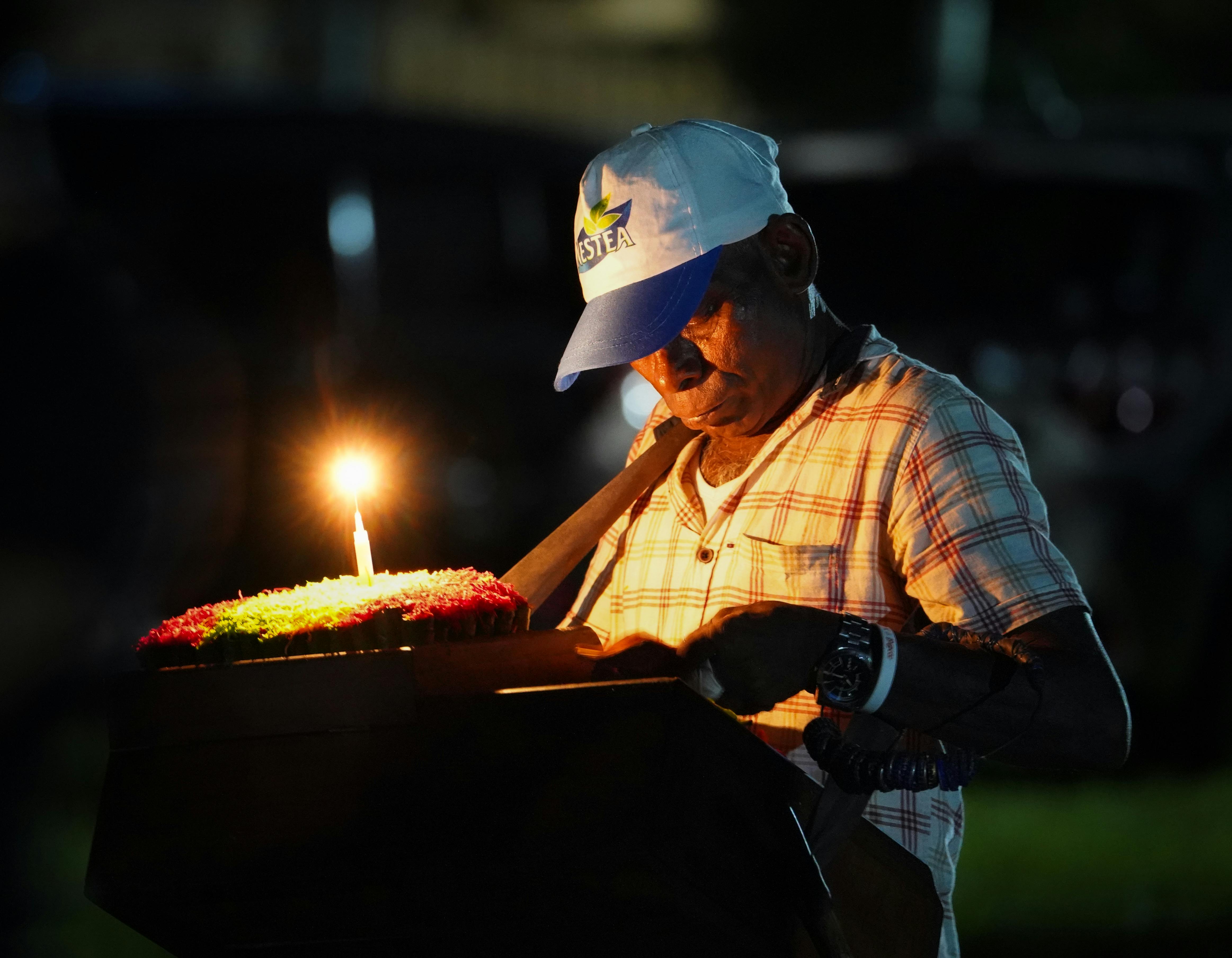 man in cap standing by burning candle