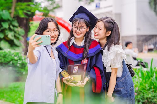 Безкоштовне стокове фото на тему «азіатські жінки, академічний капелюх, беручи selfie»