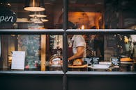 透过窗户，可以看到伦敦温暖的面包店场景，展示着糕点和忙碌的厨师