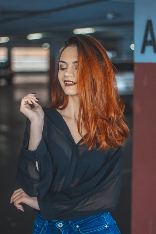 Woman Looking Downwards While Smiling at Underground Parking Space